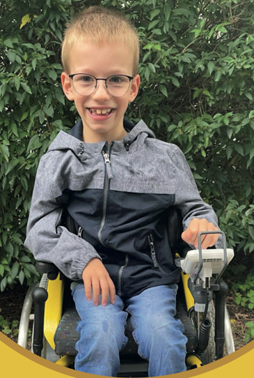 Benjamin sitzt lächelnd auf seinem Rollstuhl
